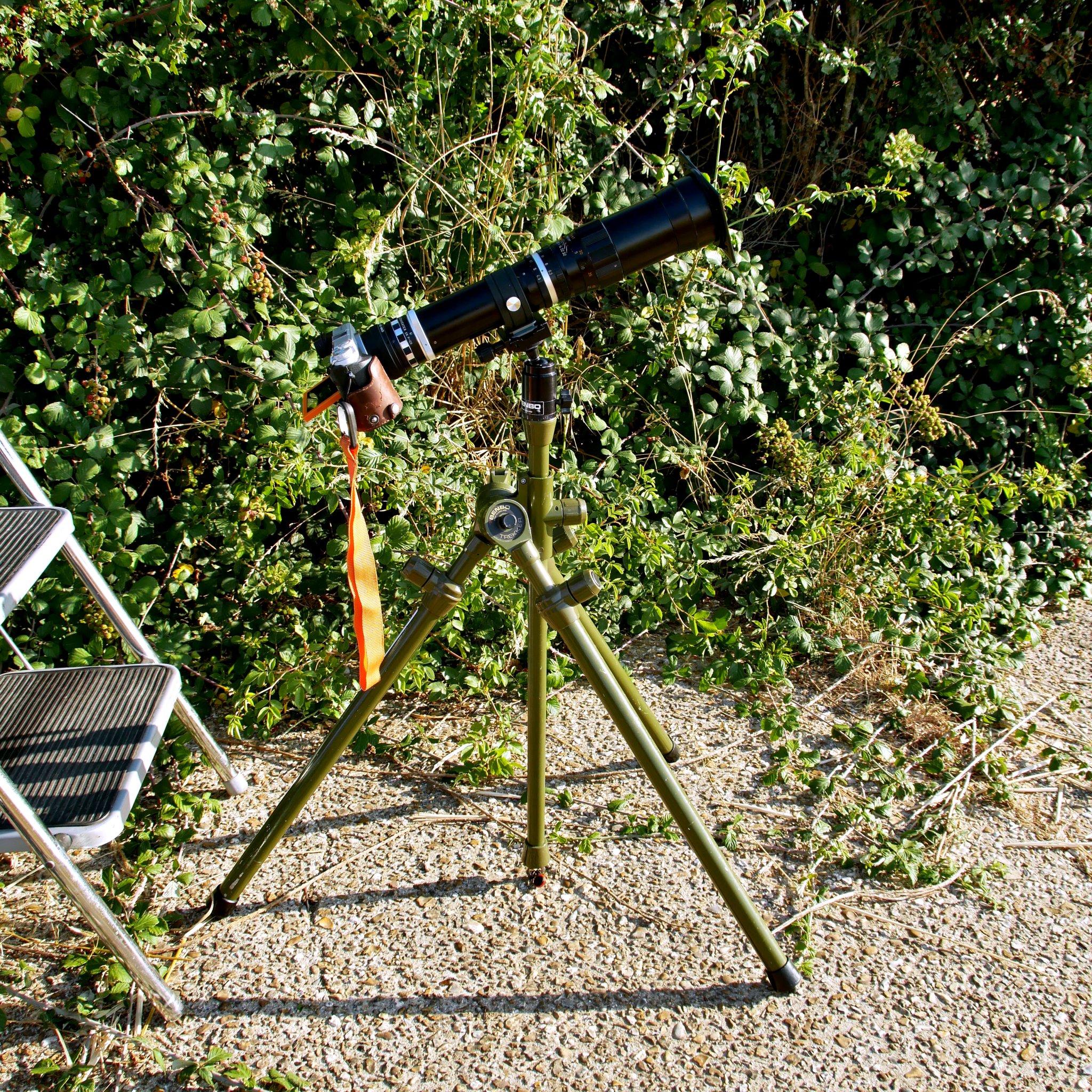 2026-08-12 Lumix DMC-GX7 camera with Hanimex 400mm lens and Tamron 2x Teleconverter mounted on Benbo Trekker tripod, with generic Arca-type quick release. Sun filter is a 90 mm x 110 mm welding glass, glued to a 72 mm - 82 mm step-up ring using black silicone bath sealer.