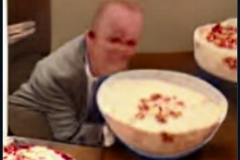 craiyon_002001_Ian_Hislop_pushed_face_first_into_a_large_bowl_of_trifle_br_