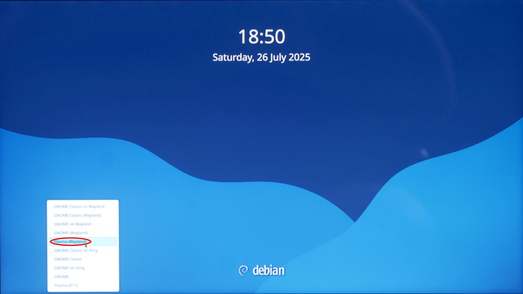 Photo shows new Debian login screen, c/w the menu that pops up, and what you need to click on that menu in order to select KDE Plasma on Wayland.